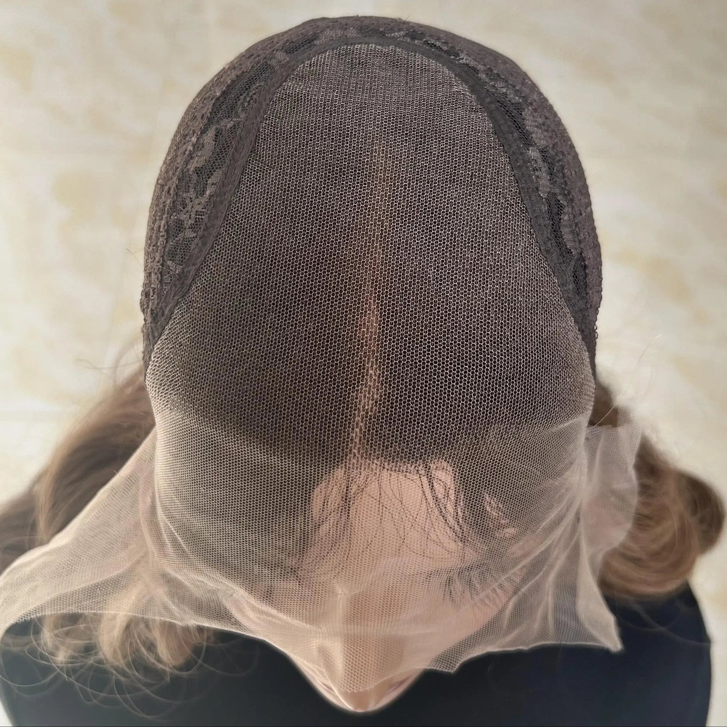 up close shot of glueless mono lace wig cap with brown balayage human hair on a neutral background