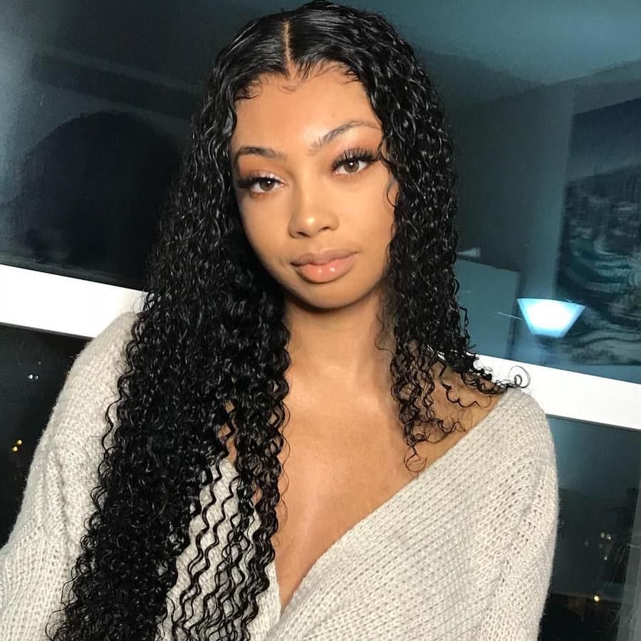 A woman demonstrates a NuHaire wig made from 100% Peruvian curly human hair, featuring 180% density. The wig showcases styling versatility, and it includes a 4x4 transparent lace closure that complements the premium curly texture of the hair.