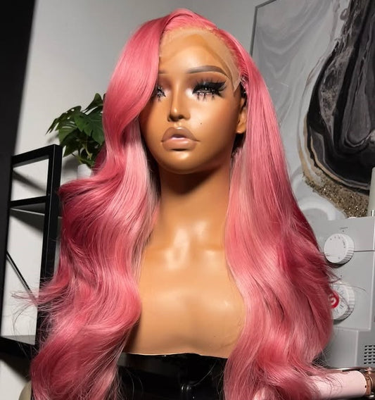 Side view of Mannequin head with NuHaire Raspberry pink balayage wig, showcasing pink body waves, premium European Human Hair Quality, 13x4 transparent lace front, and natural hairline in a room setting.