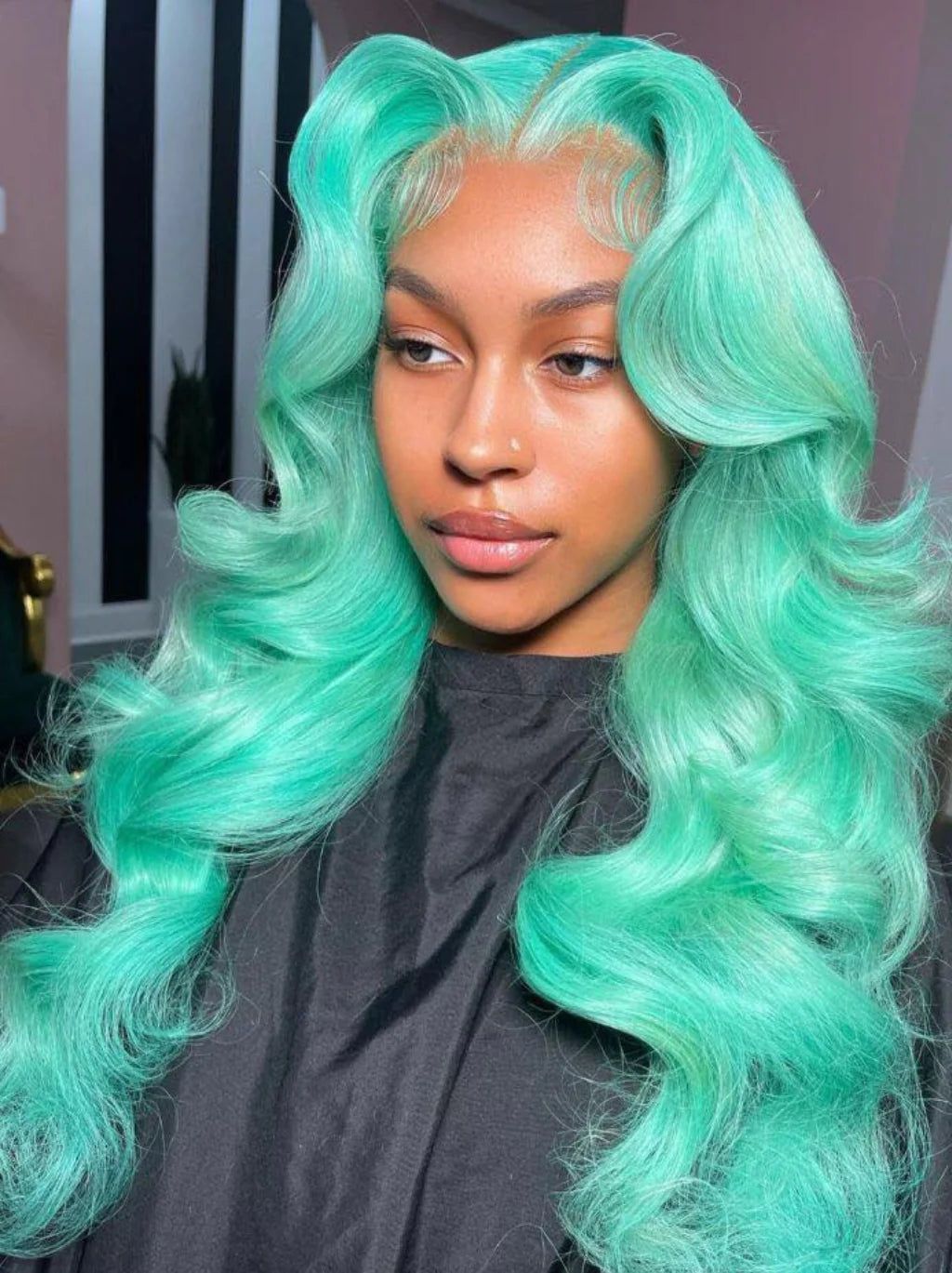 A model wearing a styled NuHaire mint green body wave lace front human hair wig with 13x4 transparent lace.