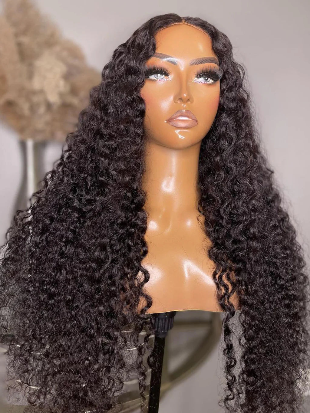 A mannequin head display of NuHaire's kinky curly 13x6 lace front wig with a pre-plucked, pre-bleached hairline. The wig features a natural black color, full density, and skin-melt HD lace.