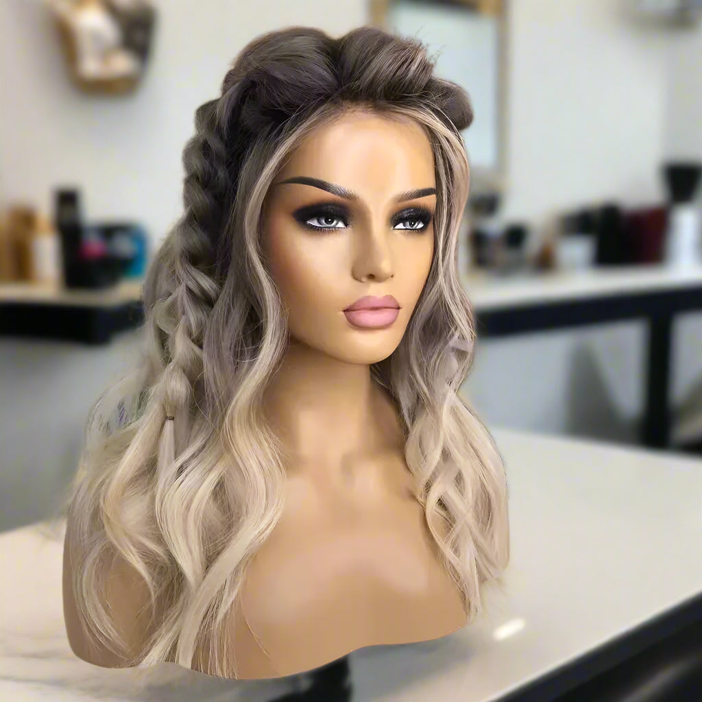 A mannequin head showcasing NuHaire's 13x4 transparent lace front Root Melt Ash Blonde Balayage Natural Wave human hair wig, highlighting the luxurious root melt balayage coloring, premium European human hair, and natural wave texture.