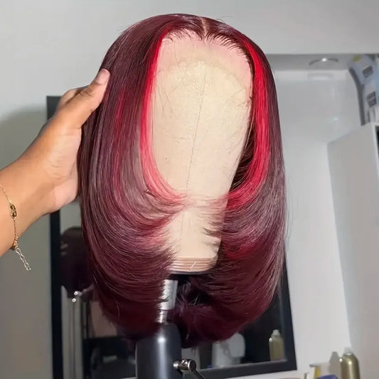 13x4 Transparent lace front highlight human hair straight bob wig displayed on mannequin head showing chunky red highlight, rich 99J burgundy color, straight texture, premium natural hairline, styling versatility, and realistic scalp with hand stroking hair in a hair salon