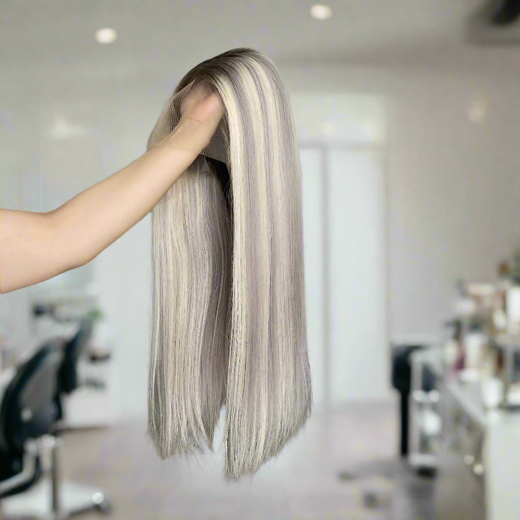 Person holding long European ash grey blond highlight straight wig in a hair salon