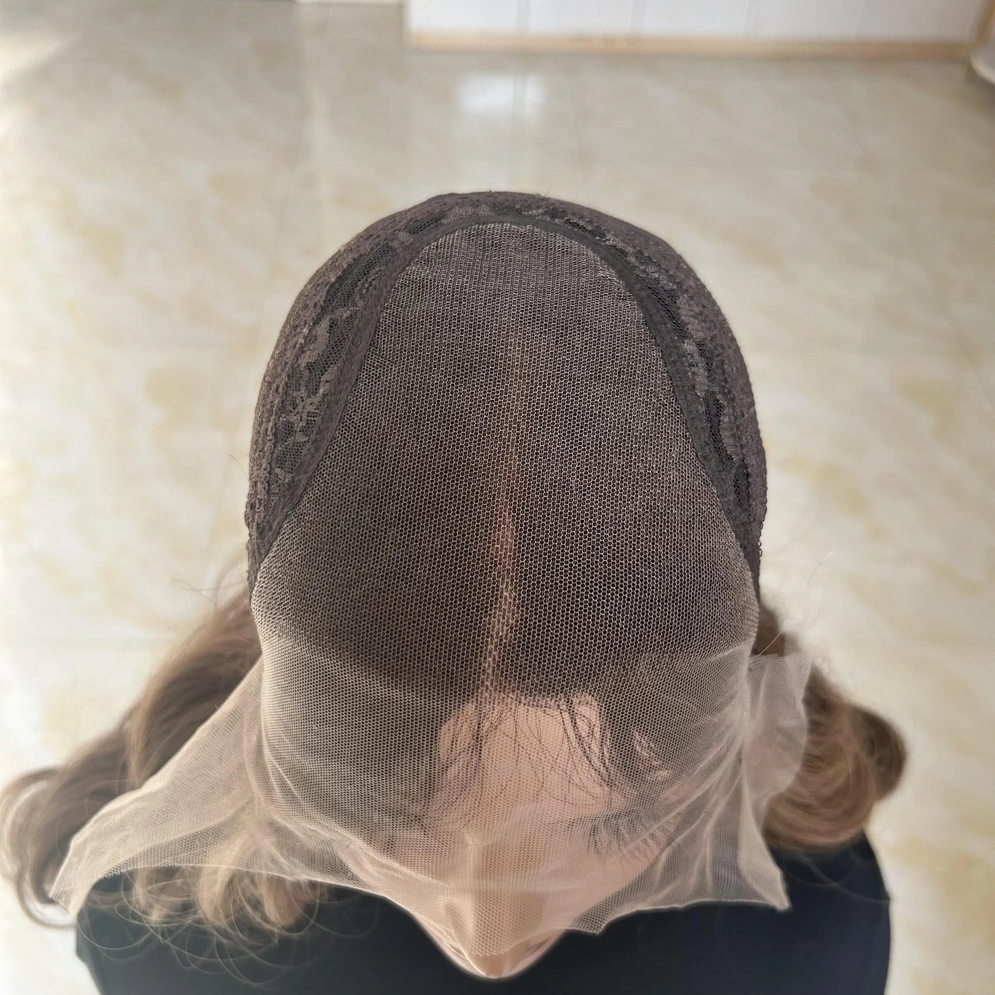 up close shot of glueless mono lace wig cap with brown balayage human hair on a neutral background