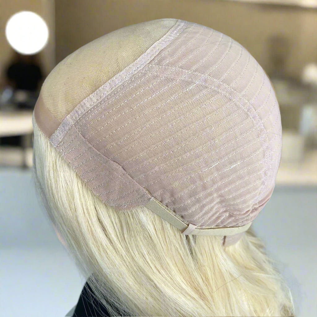 Close-up image of a beige, mono-lace, 9x5 glueless cap in a hair salon setting.