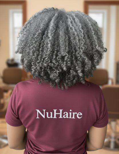 Person wearing a gray 'NuHaire' shirt with curly hair, standing in a room.
