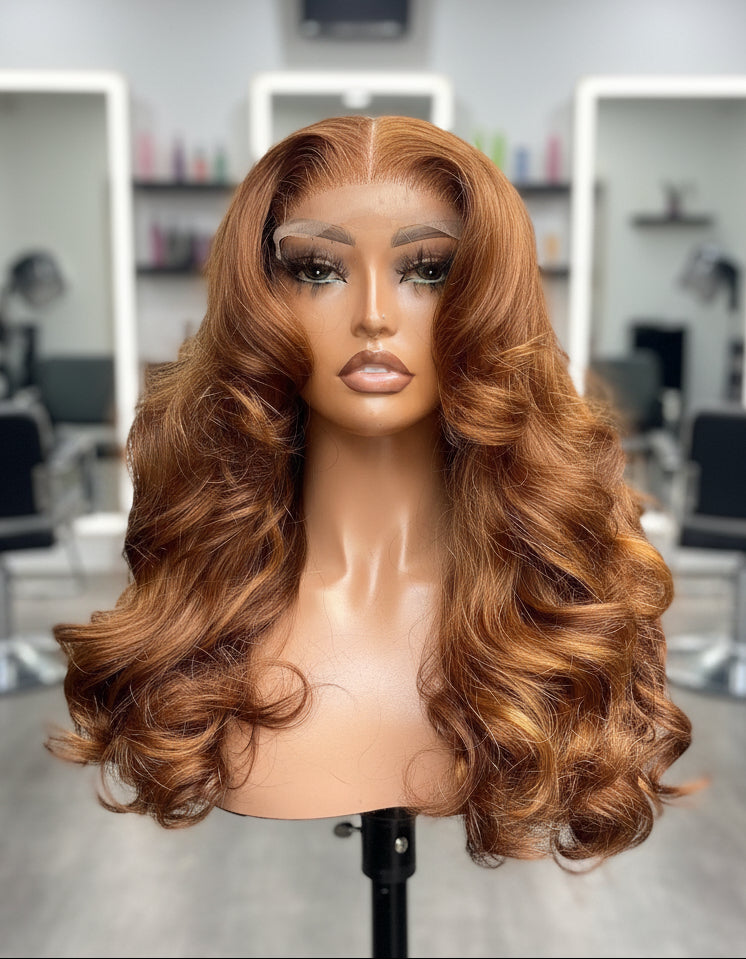 Front view of A NuHaire Human Hair wig with a 13x4 transparent lace front featuring a flowing natural wavy texture and ginger brown ombre color, displayed on a mannequin head.