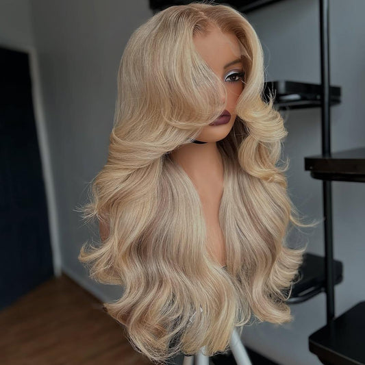 A mannequin showcases NuHaire's Ash Blonde Ombre Layered Cut Loose Wave Wig, featuring a brown root that blends into ash blonde highlights. This 250% density human hair wig offers a layered cut, loose wave texture, and various transparent lace size options for a natural hairline.