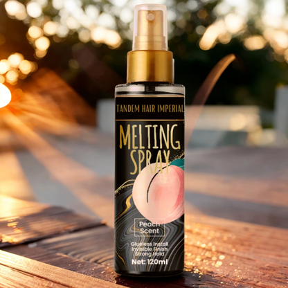 A bottle of Lace Melting Spray with a peach scent, placed on a wooden surface with a warm sunlight background.