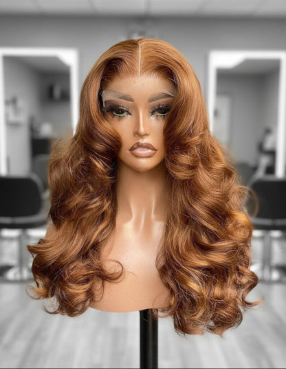 A NuHaire Human Hair wig with a 13x4 transparent lace front featuring a flowing natural wavy texture and ginger brown ombre color, displayed on a mannequin head.