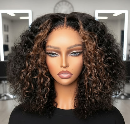 Another view of Mannequin head featuring NuHaire's Caramel Blonde Highlight Curly Bob Wig, showcasing a flawless caramel blonde highlight, premium human hair quality, 13x4 HD lace front, natural hairline, and bouncy loose curl texture against a gray background.