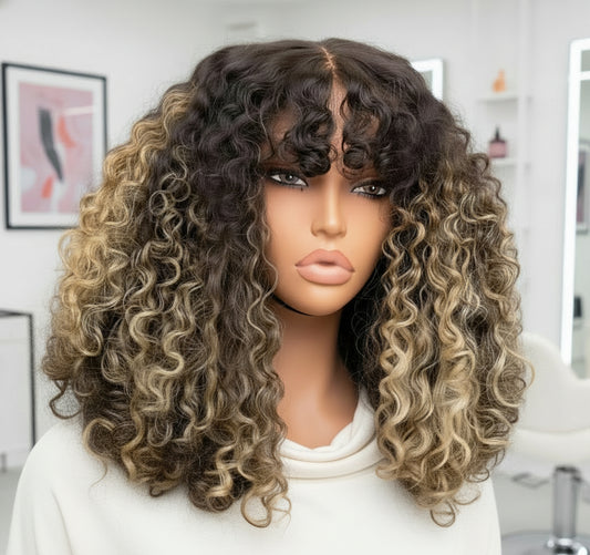 The mannequin showcases NuHaire's Honey Blonde Balayage Highlight Afro Kinky Curly Wig with Bangs, featuring a dark brown base with honey blonde highlights, a kinky curly texture, made from premium human hair, and designed with a glueless 5x5 lace.
