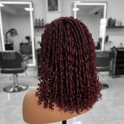 Side view of Mannequin head featuring a NuHaire burgundy pixie curly wig, showcasing rich burgundy 99J color, with bouncy, combed-out pixie curls and thin transparent lace options available in 4x4 and 13x4.