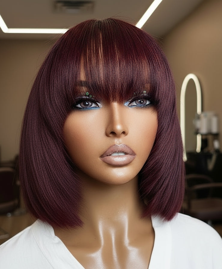 A mannequin displaying NuHaire's Burgundy Straight Bob with Bangs, with a hand showcasing a flawless Burgundy 99j hair color, premium human hair quality, glueless installation, and silky straight texture.